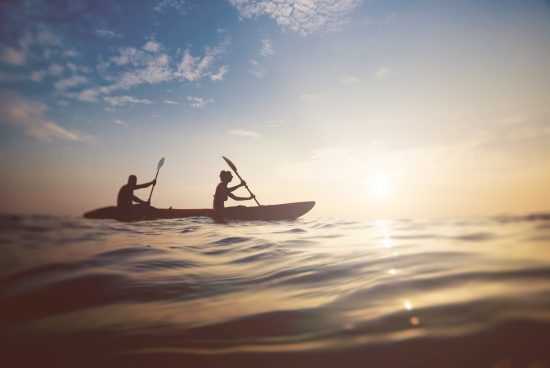 A couple kayaking at sunset creates a simple active lifestyle stock photo