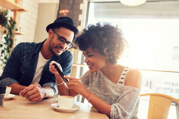 stock photo showing a couple using a cell phone to stay connected in a coffee shop